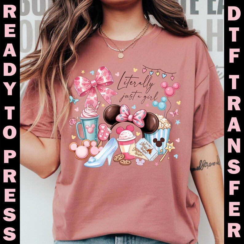 Puede incluir: Camiseta rosa polvoriento con un gr&aacute;fico colorido que presenta orejas de Minnie Mouse, un lazo y el texto "Literally just a girl". El dise&ntilde;o incluye un lazo, helado, un tac&oacute;n alto y palomitas de ma&iacute;z.