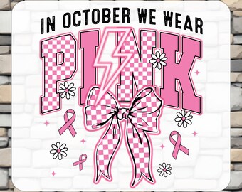 May include: A DTF transfer sheet featuring the text IN OCTOBER WE WEAR PINK in black letters. The word PINK is in a large pink and white checkered font with a lightning bolt, a checkered bow, small daisies, and pink awareness ribbons.