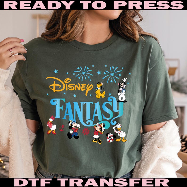 K&ouml;nnte beinhalten: Dunkelgr&uuml;nes T-Shirt mit dem Schriftzug "Disney Fantasy" in Gelb und Blau, mit Zeichentrickfiguren wie Micky Maus, Donald Duck und Goofy. Das Design umfasst Feuerwerk und Sterne.