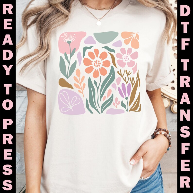 May include: Cream-colored t-shirt featuring a colorful floral design in a square arrangement. The design includes flowers in shades of peach, pink, and purple, with green leaves and accents. The words "READY TO PRESS" and "DTF TRANSFER" are printed vertically on the sides.