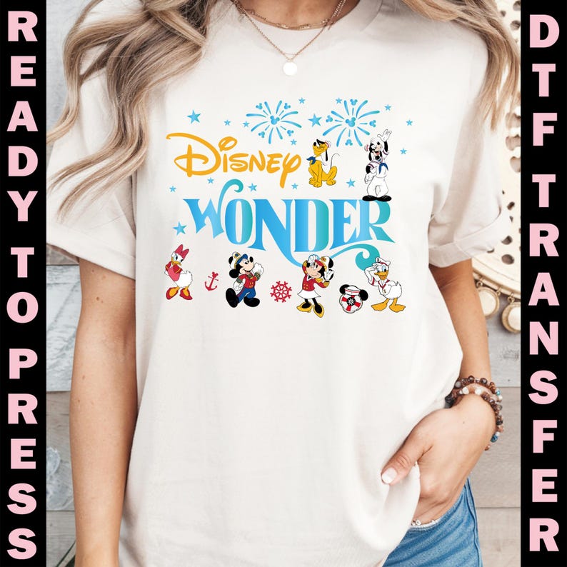 K&ouml;nnte beinhalten: Ein cremefarbenes T-Shirt mit dem Text "Disney Wonder" in Blau und Gold, mit verschiedenen Disney-Figuren. Das Design umfasst Feuerwerk und Sterne. Die W&ouml;rter "Ready to Press" und "DTF Transfer" sind an den Seiten aufgedruckt.