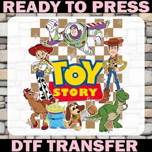 May include: A DTF (Direct to Film) transfer featuring characters from the animated film "Toy Story." The design includes Buzz Lightyear, Woody, Jessie, and other characters, with the words "TOY STORY" in large yellow letters. The words "READY TO PRESS" and "DTF TRANSFER" are also present.