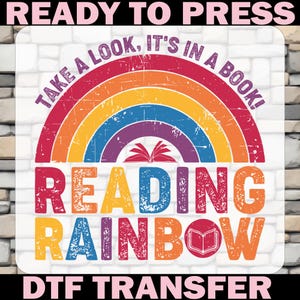 May include: A colorful DTF transfer design featuring a rainbow with the words "TAKE A LOOK, IT'S IN A BOOK!" and "READING RAINBOW". The design includes an open book graphic and is set against a white brick background.