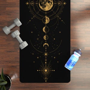 Peut inclure: Tapis de yoga noir avec un motif céleste doré représentant les phases de la lune, des étoiles et des formes géométriques. Deux haltères grises et une bouteille d'eau bleue sont sur le sol en bois.