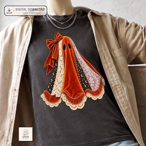 May include: A dark gray t-shirt featuring a graphic of a ghost draped in orange velvet fabric, adorned with a large orange bow, cream-colored lace trim, and panels displaying moon and star patterns. The ghost has two black oval eyes.