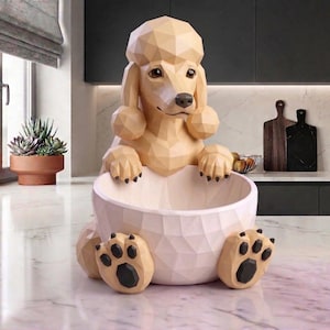 May include: A beige geometric poodle sculpture with a bowl-shaped body. The dog's head and paws are visible, with the paws resting on the base. The bowl is light pink, and the dog's paws have black pads. The sculpture is a decorative item.