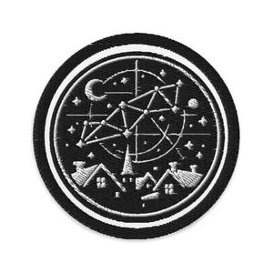 Op de afbeelding: Geborduurde ronde patch met een zwarte achtergrond en een wit hemels ontwerp. Het ontwerp omvat een maan, sterren, sterrenbeelden en huizen. De patch heeft een zwarte rand met een witte streep.