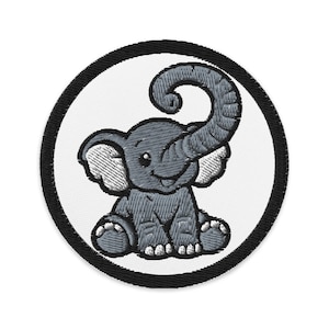 Op de afbeelding: Geborduurde patch met een grijze cartoonolifant met een gekrulde slurf, zittend. De olifant staat tegen een witte achtergrond, omlijst door een zwarte cirkelvormige rand. De olifant heeft grote oren en een glimlachende uitdrukking.