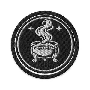 Può includere: Toppa ricamata rotonda nera con un calderone bianco con fiamme e due stelle. La toppa ha un bordo bianco ed è adatta per abbigliamento o accessori.