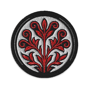 May include: Embroidered patch with a red floral design on a white background, framed by a black border. The detailed embroidery features a symmetrical, stylized plant motif, ideal for clothing or craft projects.