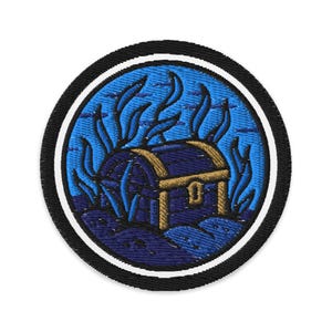 Könnte beinhalten: Gestickter Aufnäher mit einer Unterwasser-Schatzkiste. Das Design umfasst einen blauen Hintergrund mit stilisierten Algen und einer gold-blauen Truhe. Der Aufnäher ist kreisförmig mit einem schwarzen Rand und weißem Akzent.