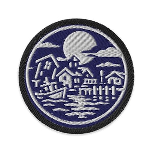 May include: Embroidered patch featuring a coastal scene with houses, water, and a full moon. The design is primarily white on a dark blue background, with a black border. The patch is circular.