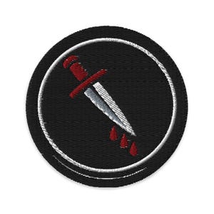 May include: Embroidered patch featuring a dagger with a silver blade and red handle, dripping with red droplets. The design is set against a black circular background, framed by a white border.