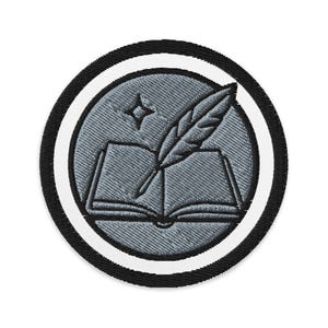 Op de afbeelding: Ronde geborduurde patch met een grijs ontwerp van een open boek, een veer en een ster. Het ontwerp staat in een grijze cirkel, omrand door een witte en zwarte ring. Geschikt voor kleding.