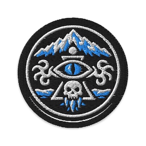 May include: Embroidered patch with a black background and a white and blue design. The design includes a mountain range, an eye, a skull, and other stylized elements. The patch is circular.