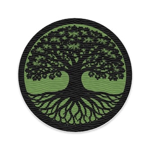 Könnte beinhalten: Runder Aufnäher mit einem schwarzen Lebensbaum-Design, einschließlich Wurzeln und Ästen, vor einem grünen Hintergrund. Der Baum ist von einem schwarzen, strukturierten Rand umgeben. Das Design steht für Wachstum und Verbundenheit.