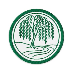 Puede incluir: Parche bordado circular con un diseño de sauce llorón verde. El árbol está sobre un fondo blanco, rodeado por un borde verde. Ideal para coser o planchar sobre ropa o accesorios. Diámetro aproximado de 7.6 cm.
