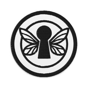 May include: Embroidered patch featuring a black keyhole with stylized wings, set within a white circle and a black border. The design is centered on a white background, creating a striking contrast. This patch is suitable for clothing or accessories.