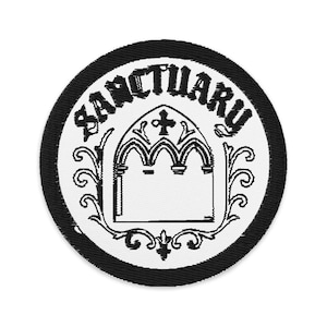May include: Circular patch with a black border and a white interior. The word "SANCTUARY" is arched across the top in black, stylized lettering. A gothic arch design with a cross is in the centre, with decorative flourishes.