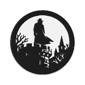 May include: A circular patch with a black and white design. It depicts a silhouette of a person in a long coat and hat on a castle wall. The background is white, with a black border, trees and a building.