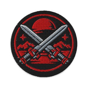 Op de afbeelding: Ronde geborduurde patch met een zwarte achtergrond, met twee gekruiste zilveren zwaarden. Een rode zon en bergketen zijn zichtbaar, evenals twee rode sterren. Het ontwerp is gedetailleerd.