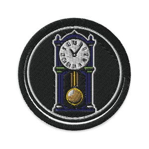 Könnte beinhalten: Runder, gestickter Aufnäher mit einer blauen Standuhr mit weißem Zifferblatt und goldenem Pendel. Die Uhr befindet sich vor einem schwarzen Hintergrund mit weißem Rand.