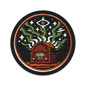 May include: Embroidered patch with a black background and a circular design. The design features a red and orange radio with green and white aurora borealis-like shapes, stars, and an eye symbol. The patch has a black border with an orange outline.