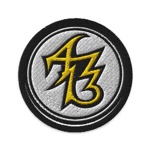 Könnte beinhalten: Runder, gestickter Aufnäher mit schwarzem Rand, weißem Innenkreis und gelbem Design. Das Design zeigt die Buchstaben "AB" und "3" in einer kräftigen, eckigen Schriftart mit Blitz-Ästhetik. Der Aufnäher ist kreisförmig.