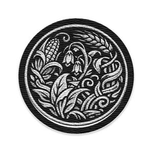 Könnte beinhalten: Ein runder, schwarz-weißer Aufnäher mit einem detaillierten botanischen Design. Das Design umfasst einen Maiskolben, Weizen, Blätter und Blumen, alles in Weiß auf schwarzem Hintergrund. Der Aufnäher hat einen strukturierten Rand.