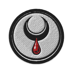 Peut inclure: Écusson brodé avec un croissant de lune et une goutte de sang rouge. Le patch a une bordure noire et un fond blanc texturé. Le motif est centré et détaillé.