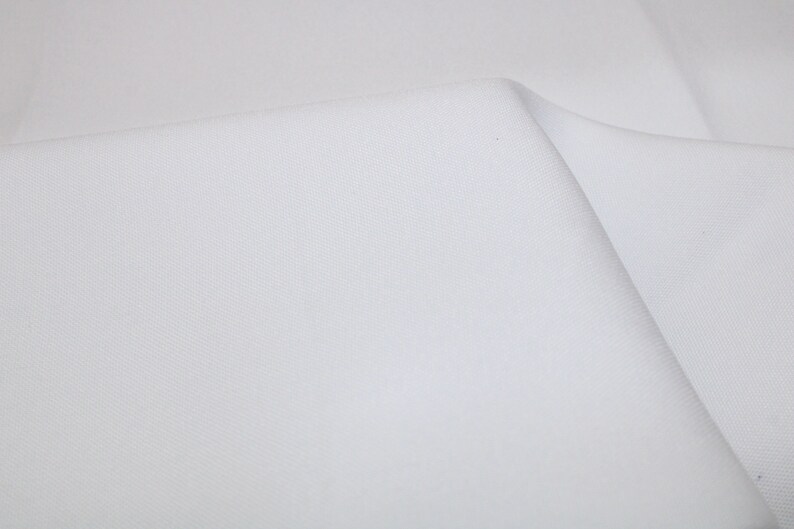 May include: White fabric with a smooth, even texture. The fabric is folded in half, creating a crease down the center.