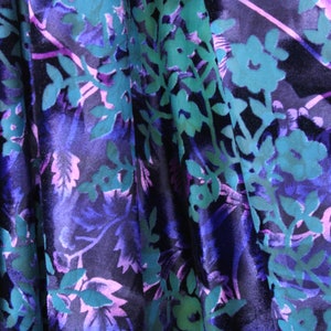 May include: A close-up of a fabric with a floral pattern. The fabric is a deep blue color with teal and pink flowers and leaves.