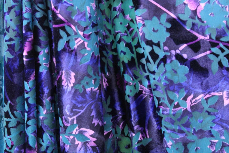 May include: A close-up of a fabric with a floral pattern. The fabric is a deep blue color with teal and pink flowers and leaves.