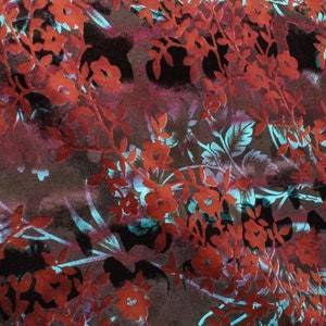 May include: A fabric with a floral pattern in shades of red, blue, and brown. The fabric has a textured, almost velvety feel.