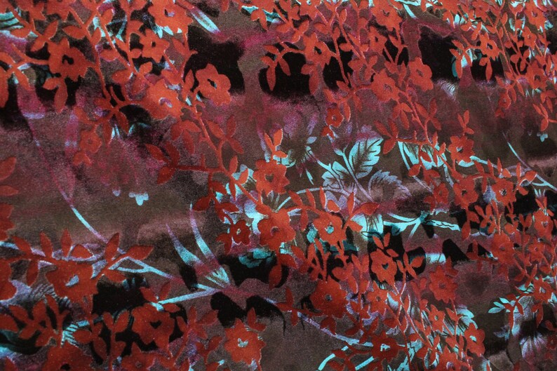 May include: A fabric with a floral pattern in shades of red, blue, and brown. The fabric has a textured, almost velvety feel.