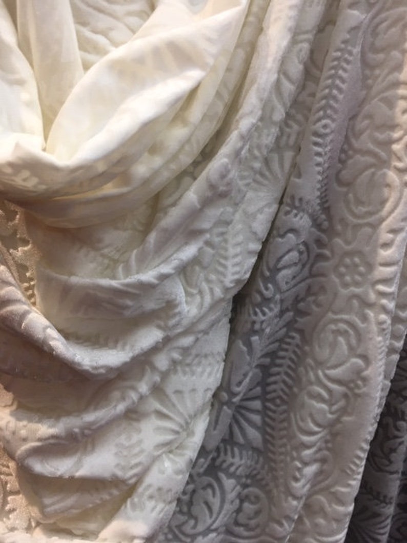 May include: Two white fabric swatches with different textures. One swatch has a smooth, plain surface, while the other has a raised, embossed pattern.