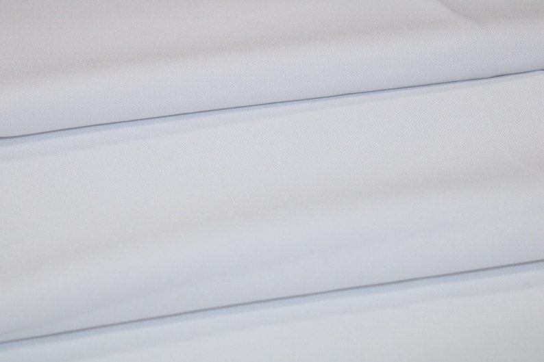May include: White fabric folded in thirds, showing the smooth texture and subtle sheen of the material.