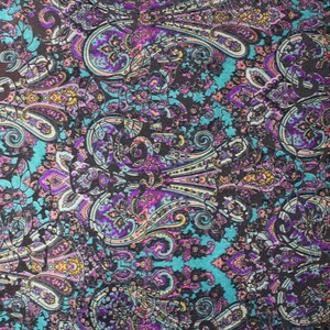 Op de afbeelding: Een tealblauwe stof met een paisley-patroon in tinten paars, roze, geel en wit.