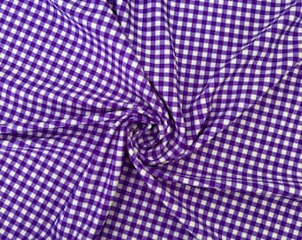 Op de afbeelding: Paars en wit gingham-stof met een geruit patroon. De stof is gevouwen en gedraaid, waardoor een wervelend effect ontstaat.