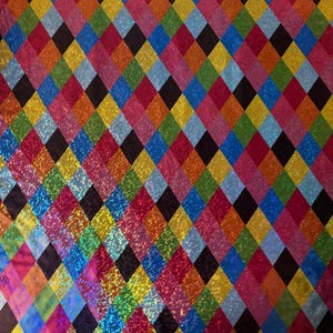 Può includere: Un vivace motivo a rombi multicolore. Il design presenta un motivo ripetuto di diamanti colorati e scintillanti in tonalità di rosso, rosa, arancione, giallo, verde, blu e nero. L'effetto complessivo è accattivante e dinamico.