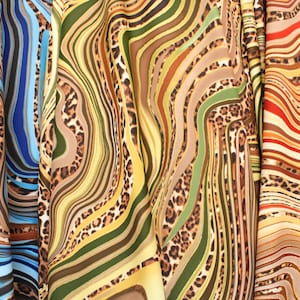 May include: Close-up of four fabric swatches with a wavy, abstract pattern in shades of blue, green, brown, and orange. The fabric has a leopard print overlay.