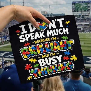 May include: Black poster with the text "I DON'T SPEAK MUCH BECAUSE I'M BRILLIANT AND I'M BUSY THINKING." The words are in white, yellow, green, blue, and red, with puzzle piece accents. A heart-shaped puzzle is at the top.