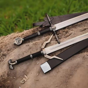May include: Two swords with silver blades and black handles rest on a textured surface. One sword has a leather sheath. The handles feature intricate designs, and the blades are sharp and reflective. The swords are likely decorative or for historical reenactment.
