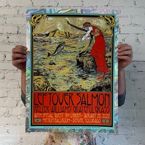 May include: A holographic concert poster for Leftover Salmon with Keller Williams' Grateful Grass. The poster features a woman playing a harp in a red dress, a fish swimming in the water, and a mountain range in the background. The text on the poster reads "Leftover Salmon, Keller Williams' Grateful Grass, with special guest Tim O'Brien, January 20, 2022, Mission Ballroom, Denver, Colorado."