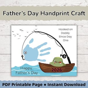 Puede incluir: Una manualidad imprimible de huella de mano para el Día del Padre con una huella azul claro en forma de pez en un sedal. El diseño incluye un barco marrón con el año 2026, un sombrero verde, pájaros y el texto Hooked on Daddy Since Day One.