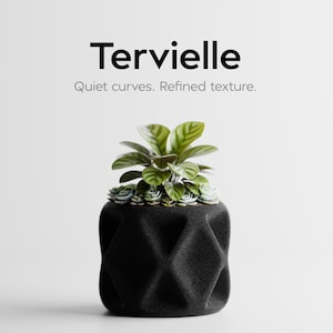May include: A black geometric planter with a small plant and succulents. The planter has a textured surface and is filled with green and white plants. The text "Tervielle" and "Quiet curves. Refined texture." are displayed above the planter.