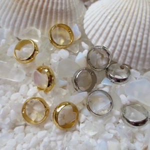 May include: A collection of gold and silver rings on a white background. The rings are arranged in a circle, with the gold rings on the outside and the silver rings on the inside.