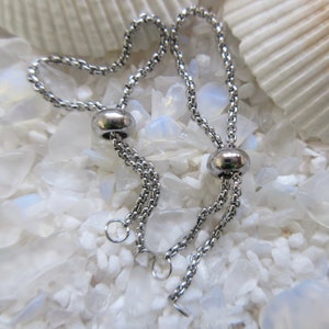 May include: Two silver chain bracelet extenders with round silver beads. The extenders are on a white background.