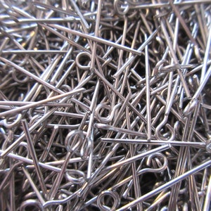 May include: A large pile of silver-colored head pins with eye loops. The pins are all the same size and are arranged in a random pattern.