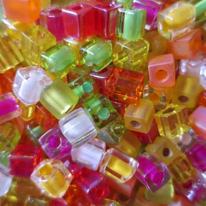 May include: A collection of colorful, translucent, square-shaped beads in various shades of green, yellow, orange, red, pink, and white.